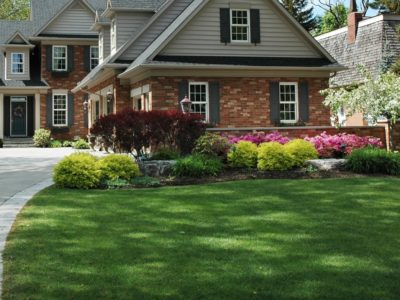 Red brick house with black shutters and pretty manicured lawn / garden